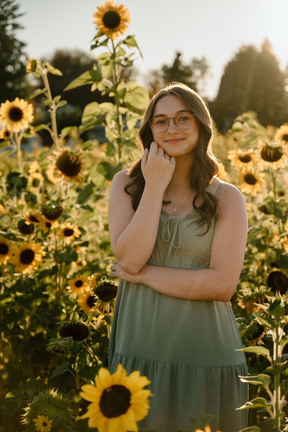 Golden hour portrait in a vibrant sunflower field wearing a sage green dress.