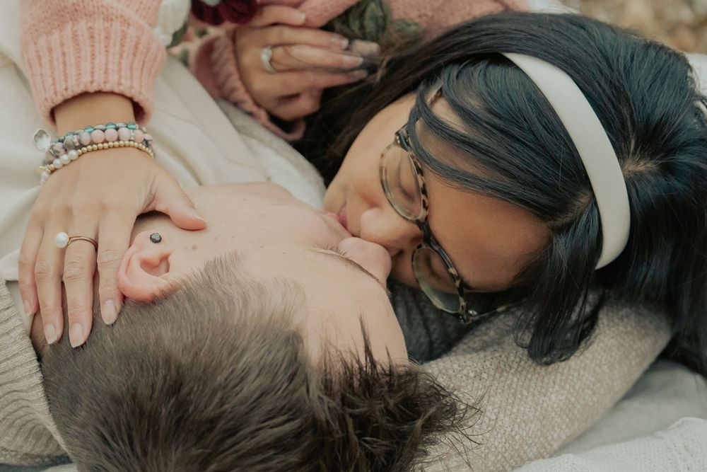 Close-up photo of a sleeping baby being gently touched by caring hands.