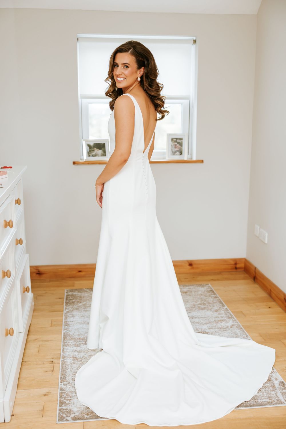 Stunning bridal gown with deep V-neck and long train showcased in a bright modern room. Castle Leslie
