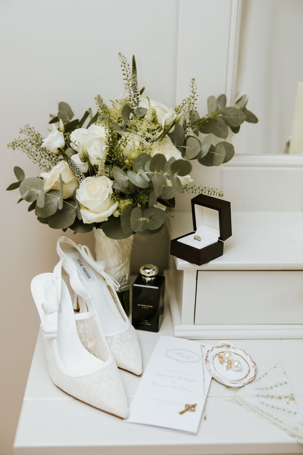 Elegant white wedding stationery and floral arrangements with eucalyptus displayed on a light surface. Castle Leslie