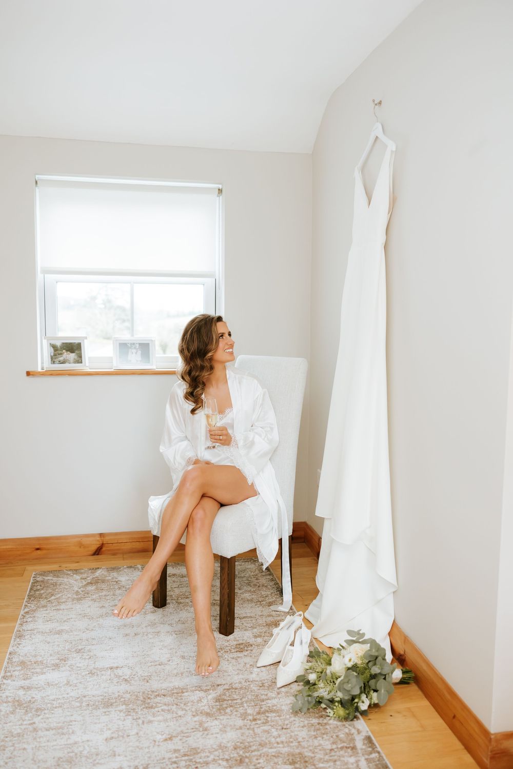 A bridal boudoir photoshoot in a bright white room with flowing curtains and wooden floors. Castle Leslie