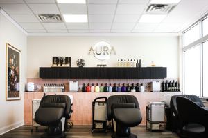 Interior view of a modern hair salon with black styling chairs, fluorescent lighting and retail product displays.