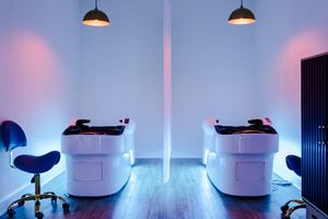 Modern office interior with colorful LED lighting and minimalist white chairs against a dark wall.