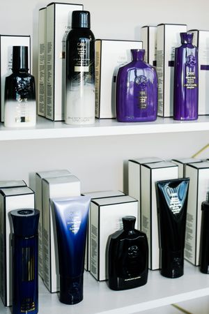 Collection of luxury perfume bottles in black, white and purple displayed on minimalist white shelves.