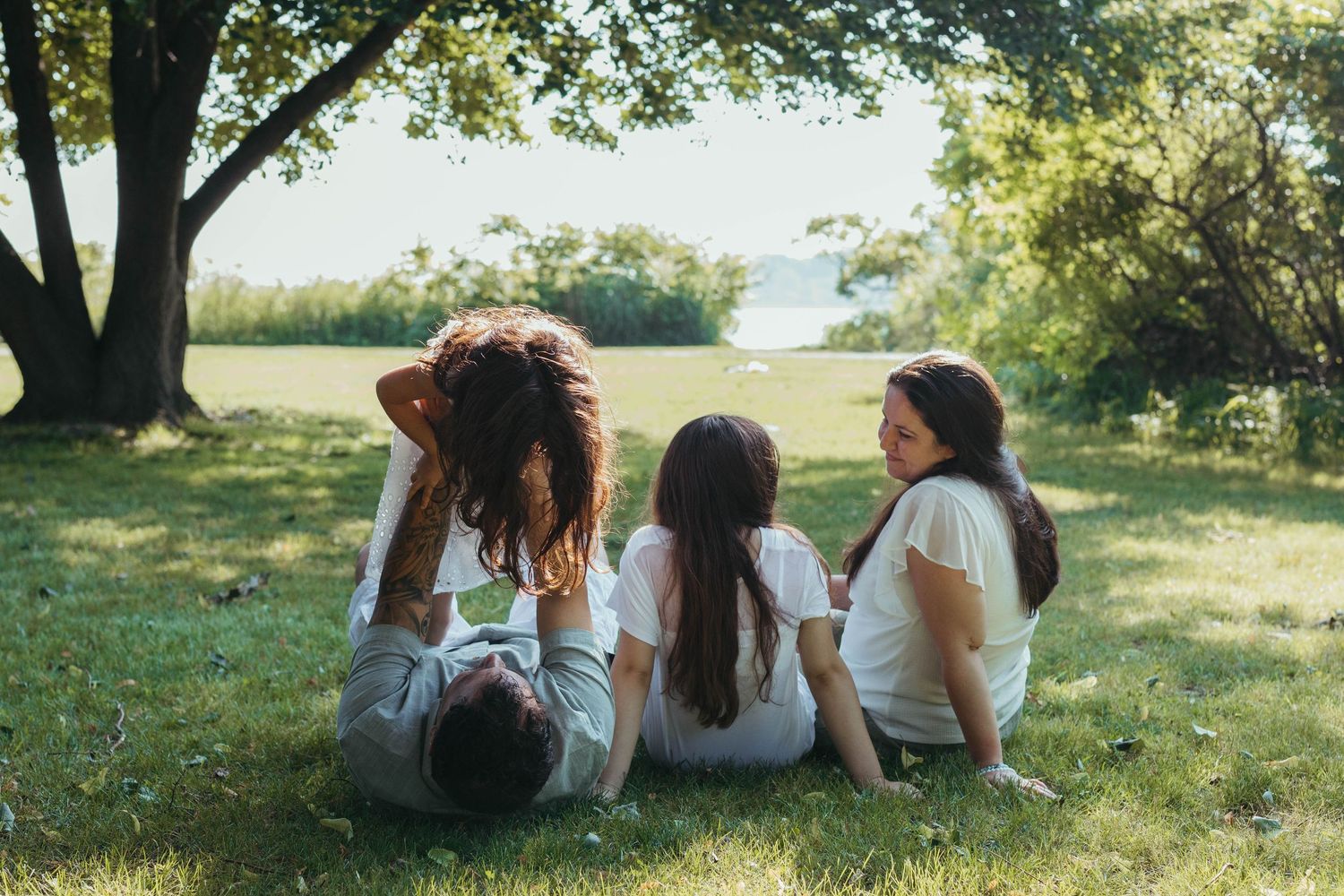 Group relaxing together under shady trees on a sunny afternoon.