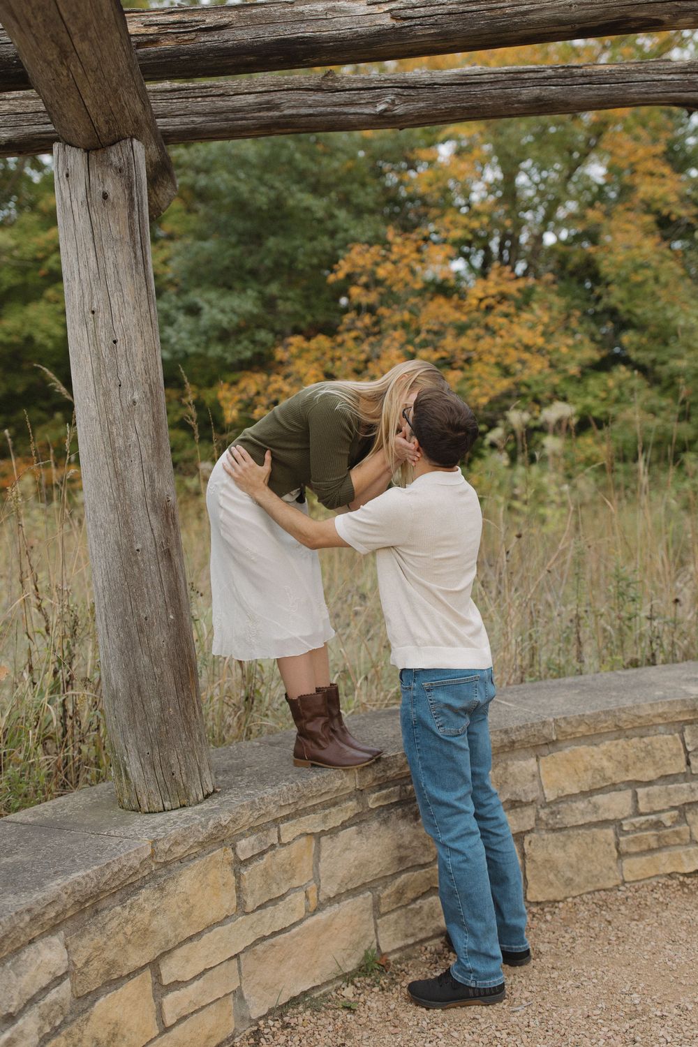 A playful moment captured between a couple by a wooden structure in a park.