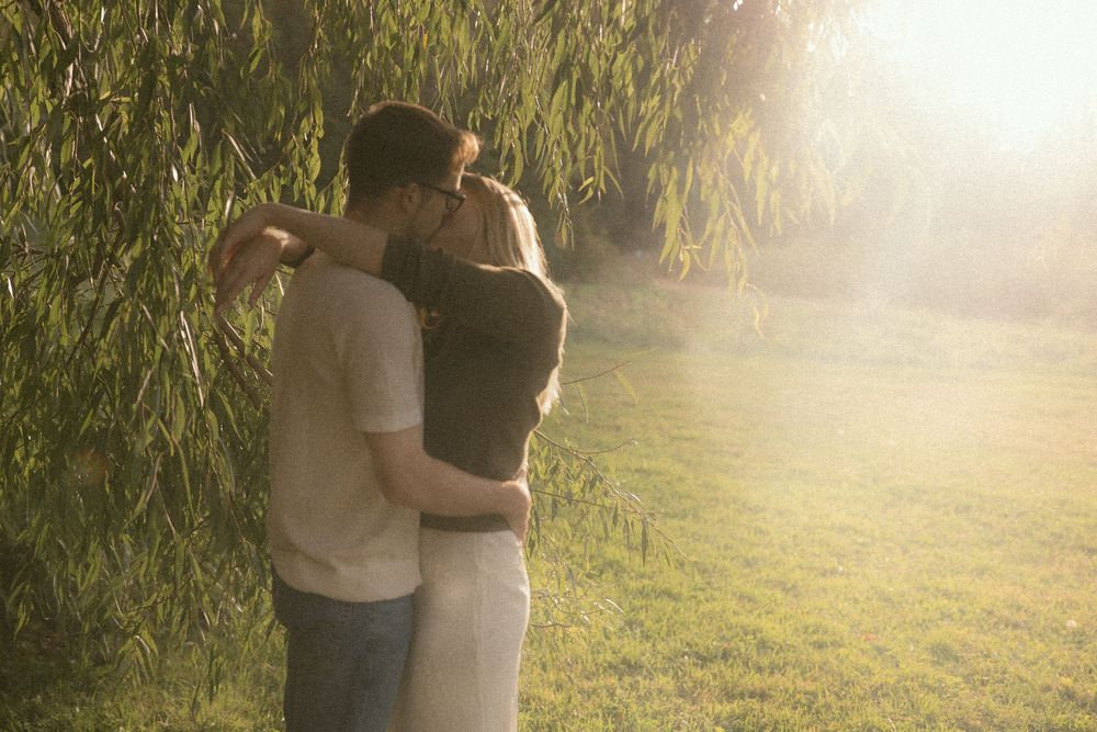 A romantic embrace captured in warm sunlight with tall grass in the background.
