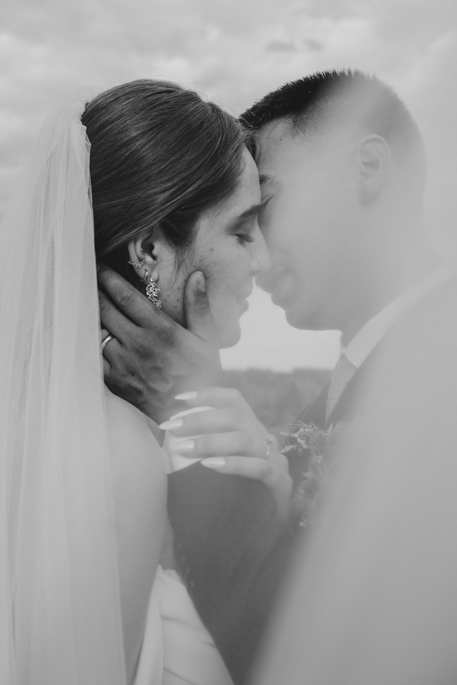Romantic black and white wedding portraits showing intimate moments between newlyweds through a soft veil.