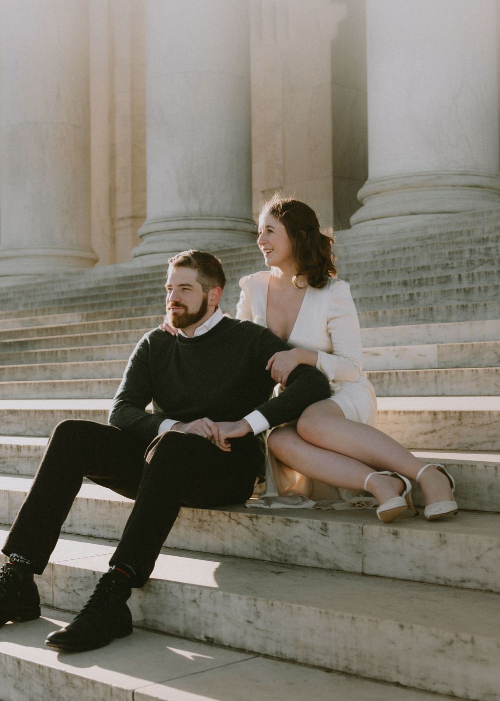 Artistic engagement photos of a couple relaxing on stone steps with elegant columns behind them.