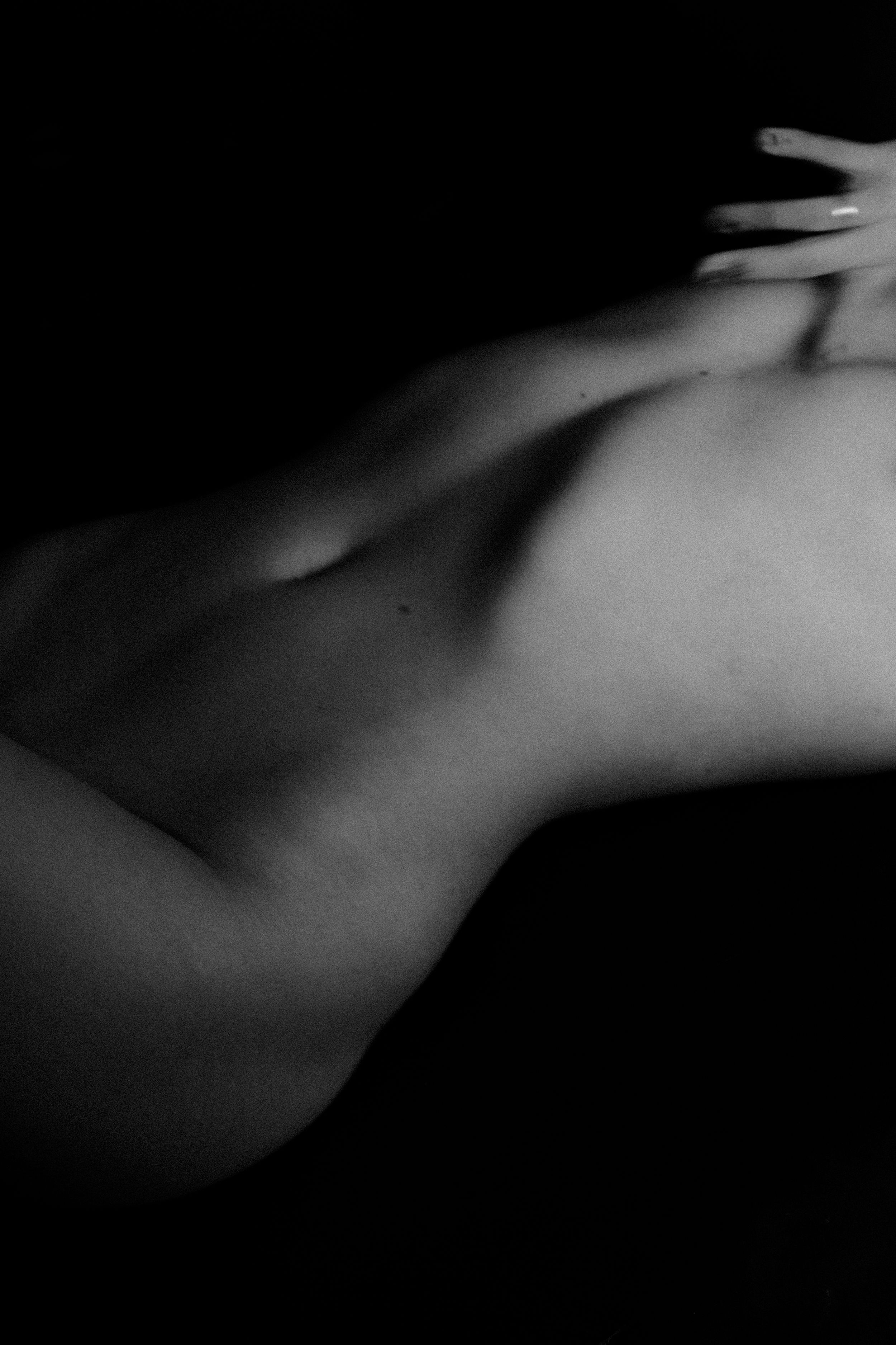 Abstract black and white close-up images showing gentle hand movements in dramatic lighting.