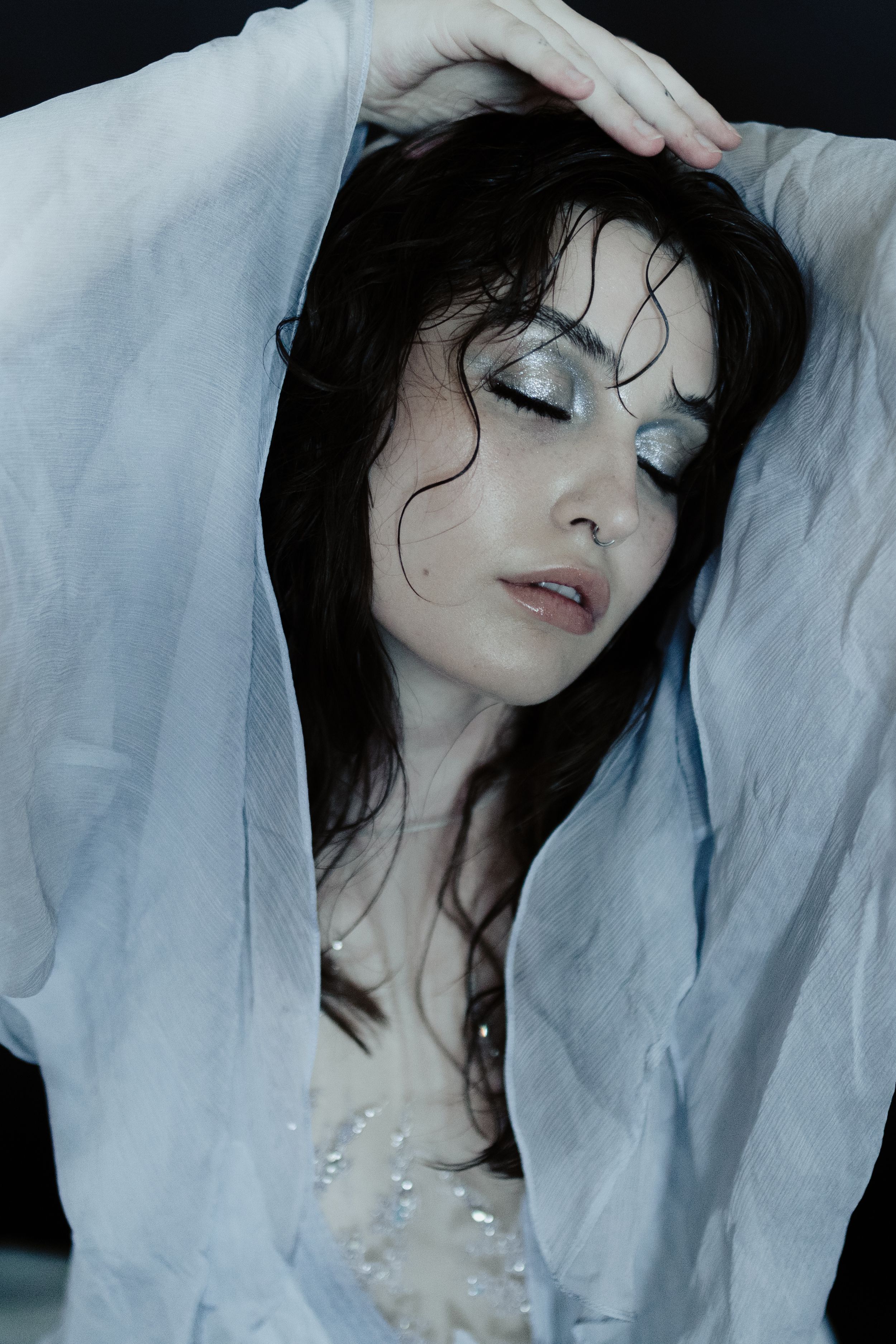 Artistic portrait series showing ethereal poses against light blue fabric with pearl necklace details.