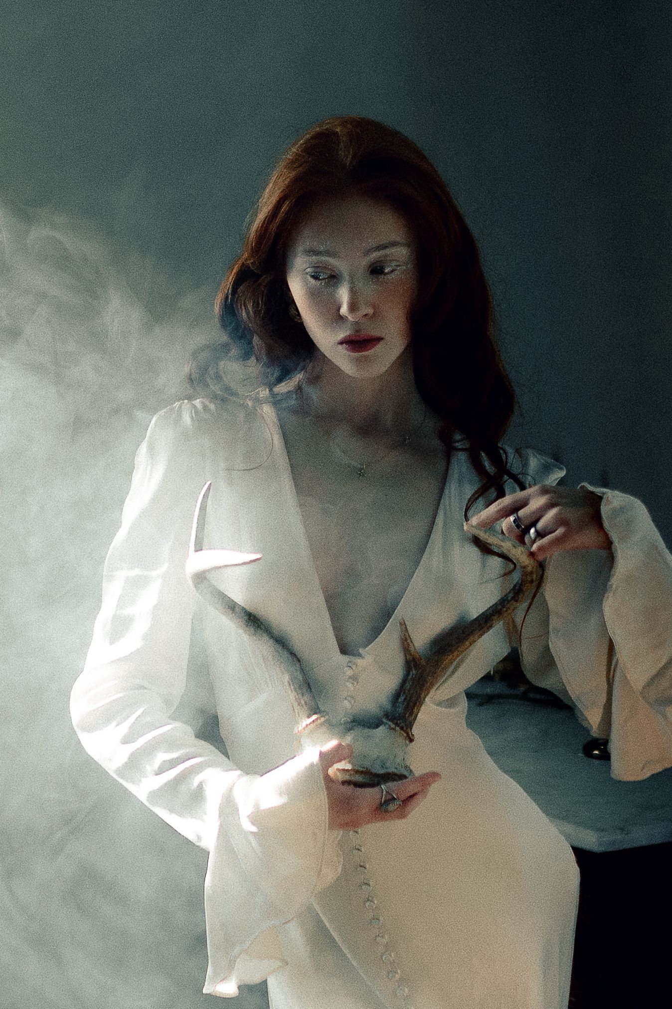 A series of atmospheric photos showing a figure in a white dress against a dark background with smoke effects.