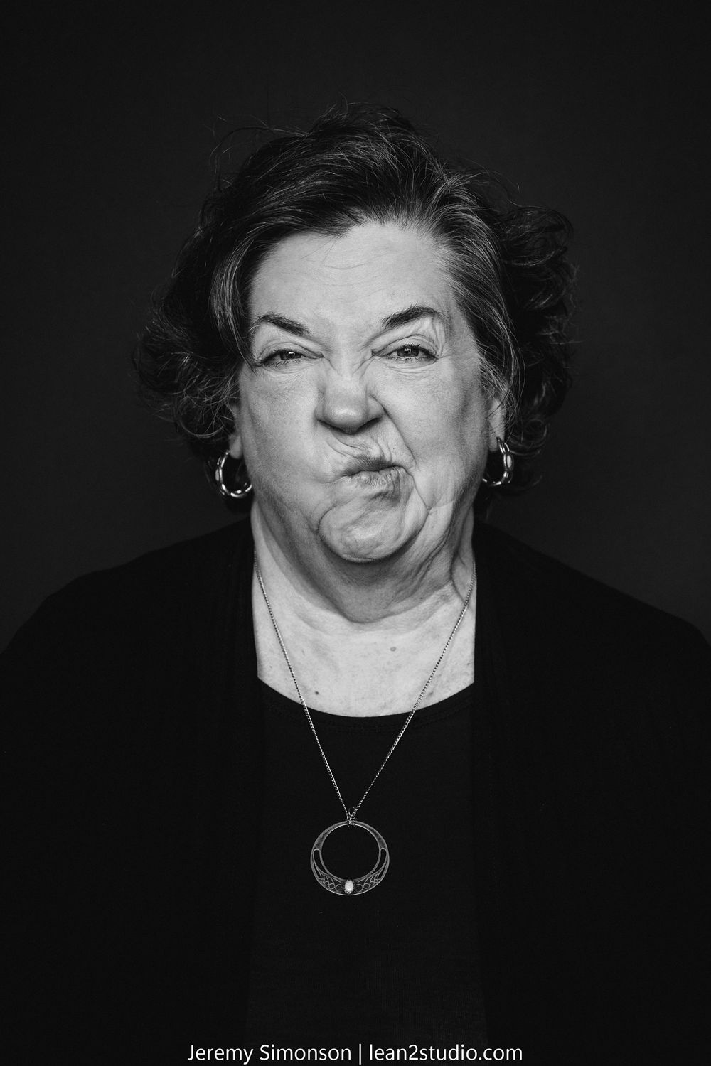 A series of black and white portraits showing a person making different playful expressions against a dark background.