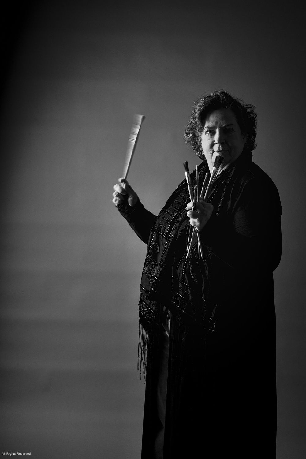 A dramatic black and white portrait series shows a figure in dark clothing gesturing expressively against a moody background.
