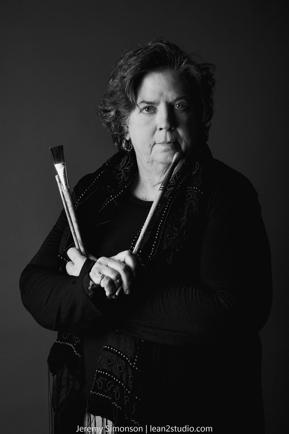 A dramatic black and white portrait series showing a figure in dark clothing holding test tubes against a shadowy background.