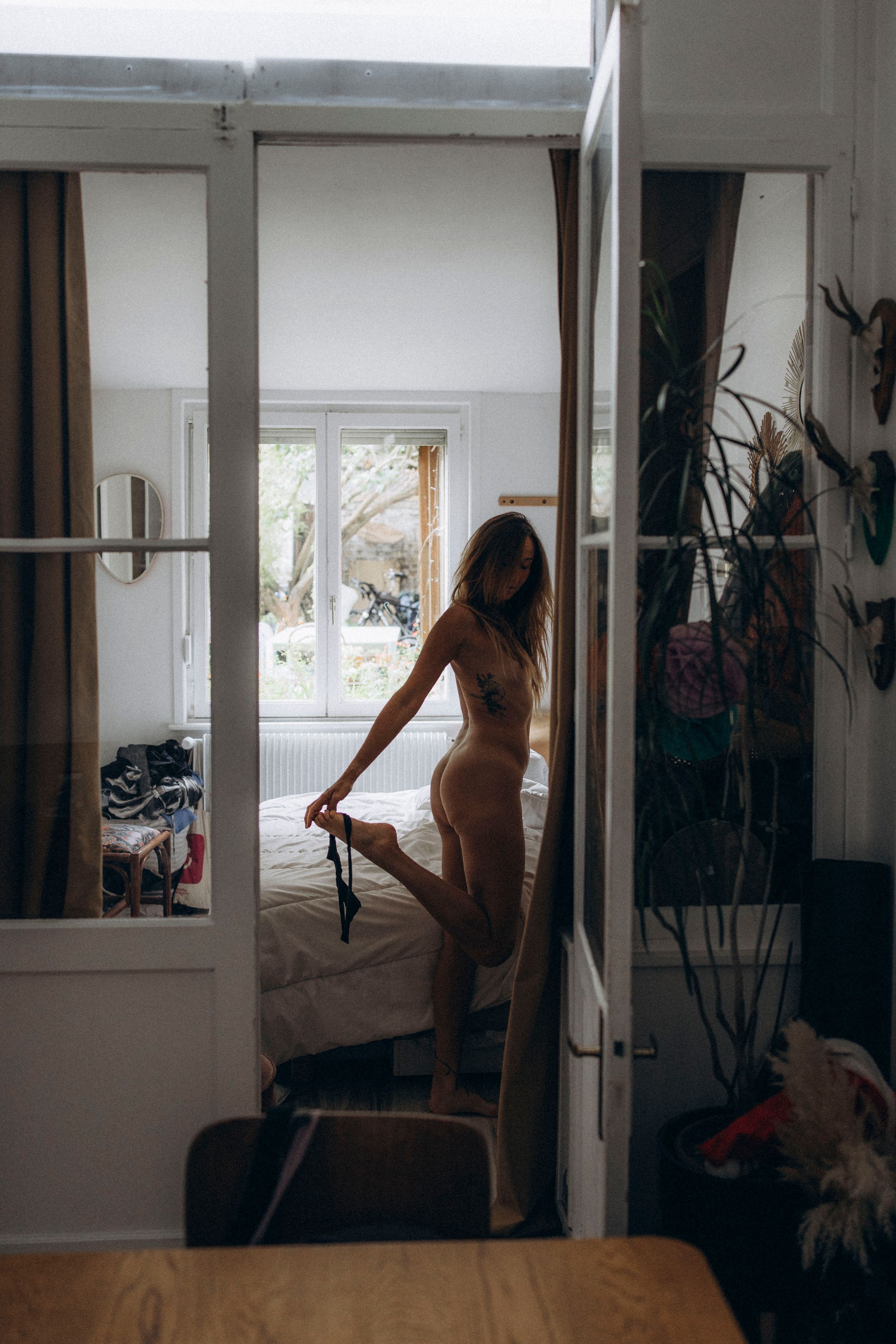 A sequence of three moody interior shots showing a figure silhouetted against bright windows in a minimalist room.