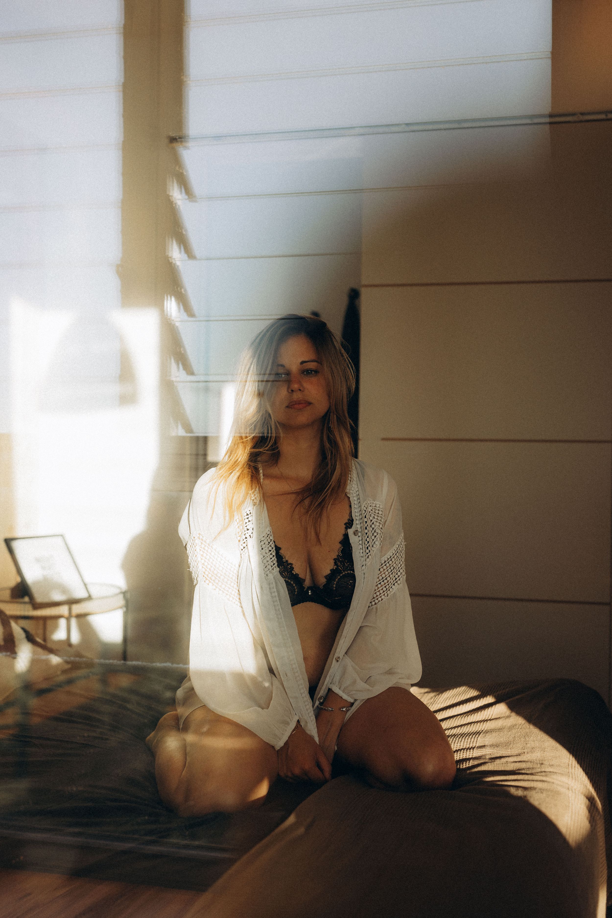 Moody boudoir photoshoot series showing a figure in white shirt against sunlit shadows on bed.