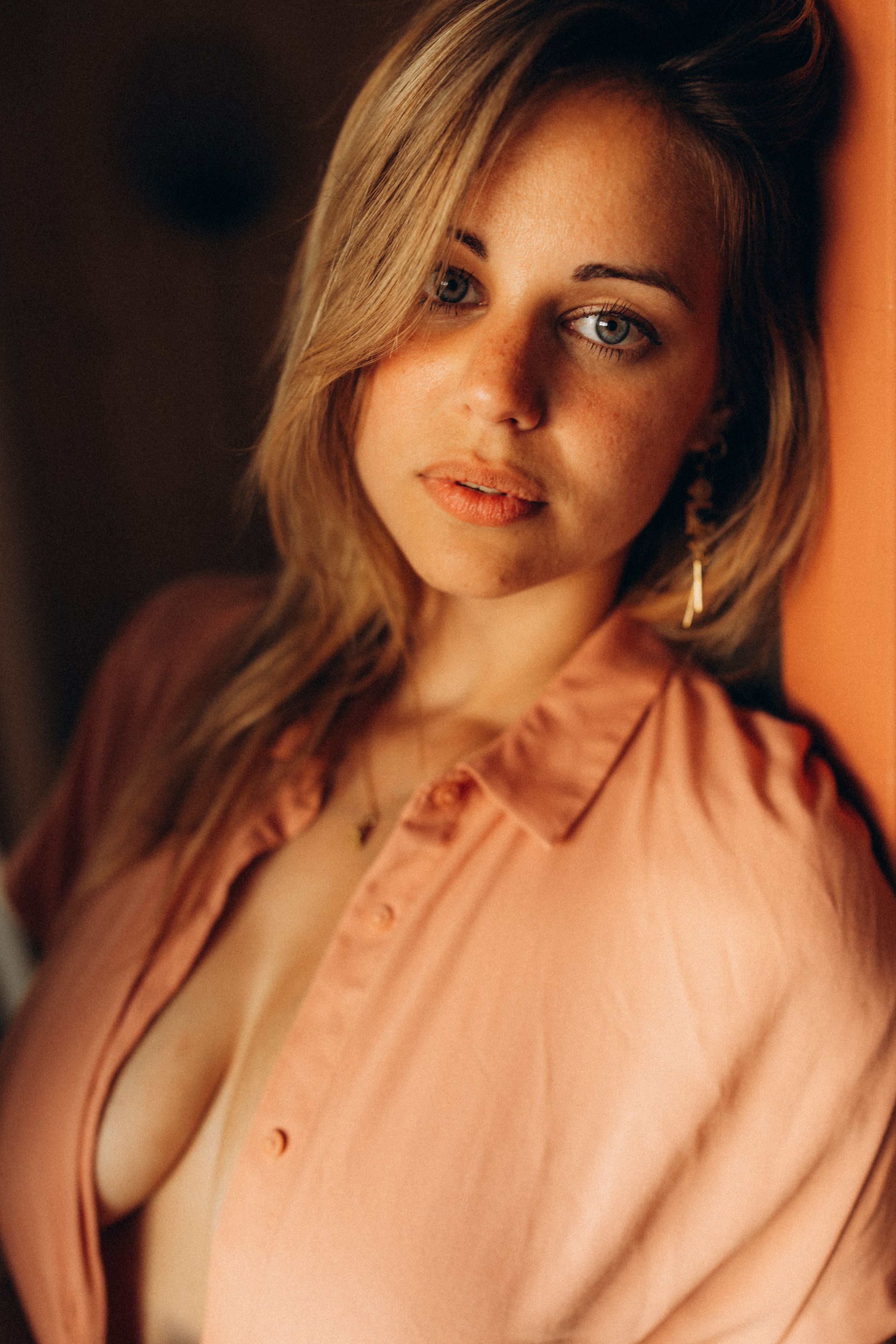 Portrait series in warm lighting showing someone in a pink sweater with soft shadows and dramatic angles.