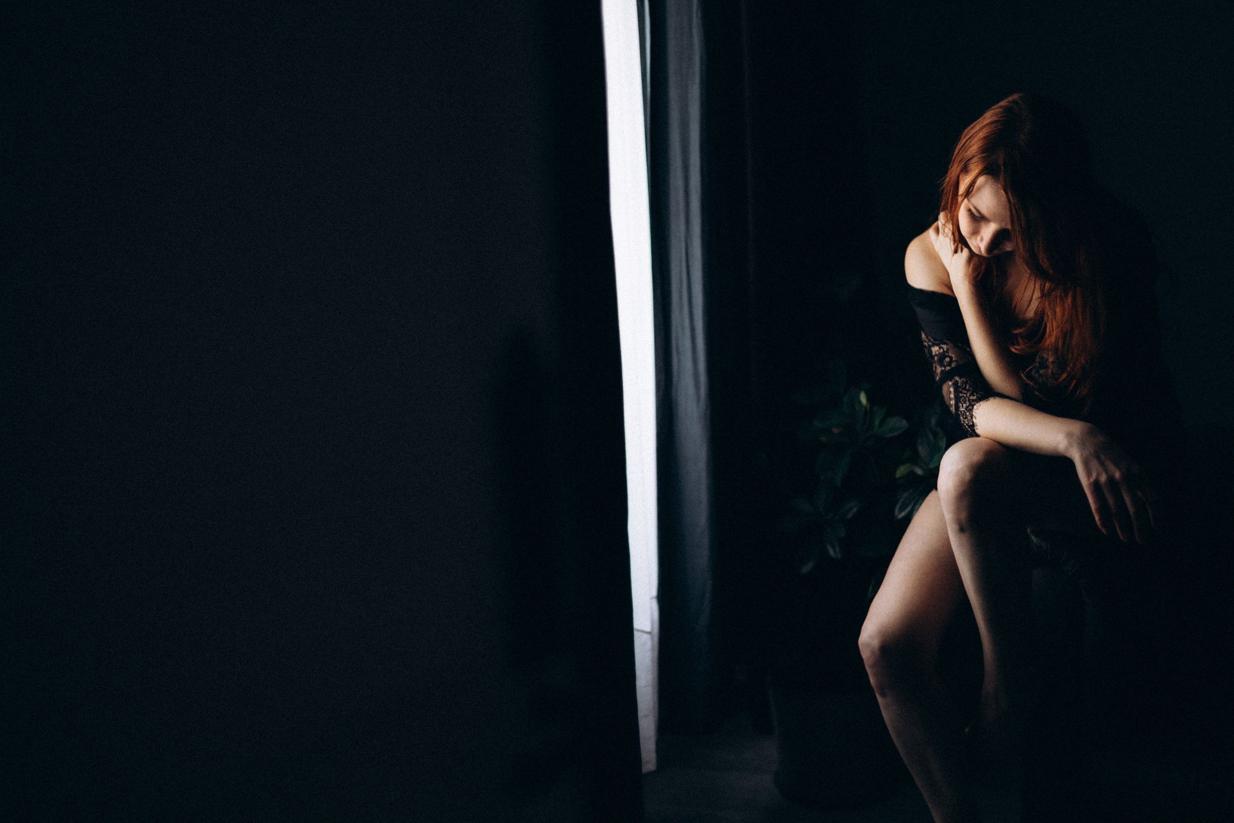 Silhouetted figure stands in dramatic lighting against a dark background creating a moody artistic portrait.