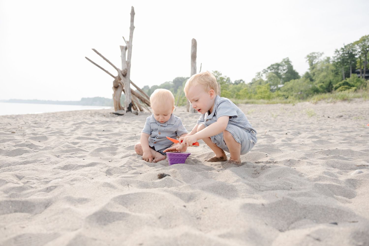 A sequence of photos shows a baby playing and crawling on a sandy beach during a sunny day.