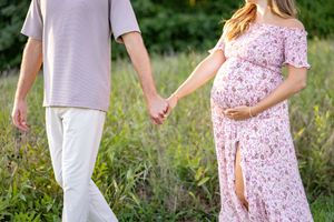 A couple poses in a wildflower field during their summer maternity photoshoot.