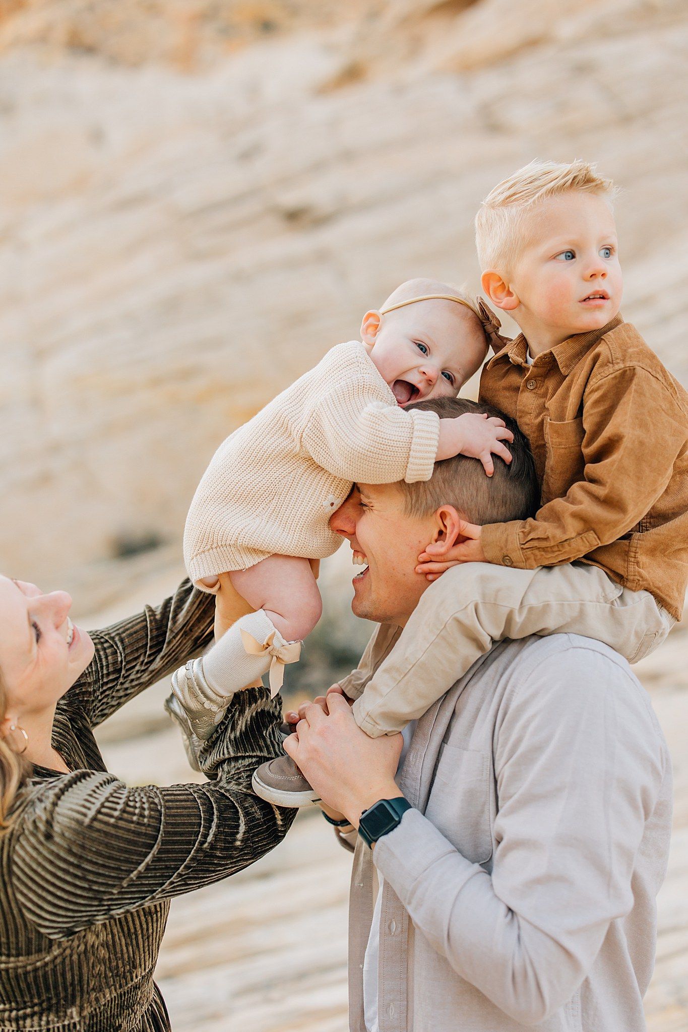 A couple embraces and laughs together against a backdrop of desert rock formations during a photo session.