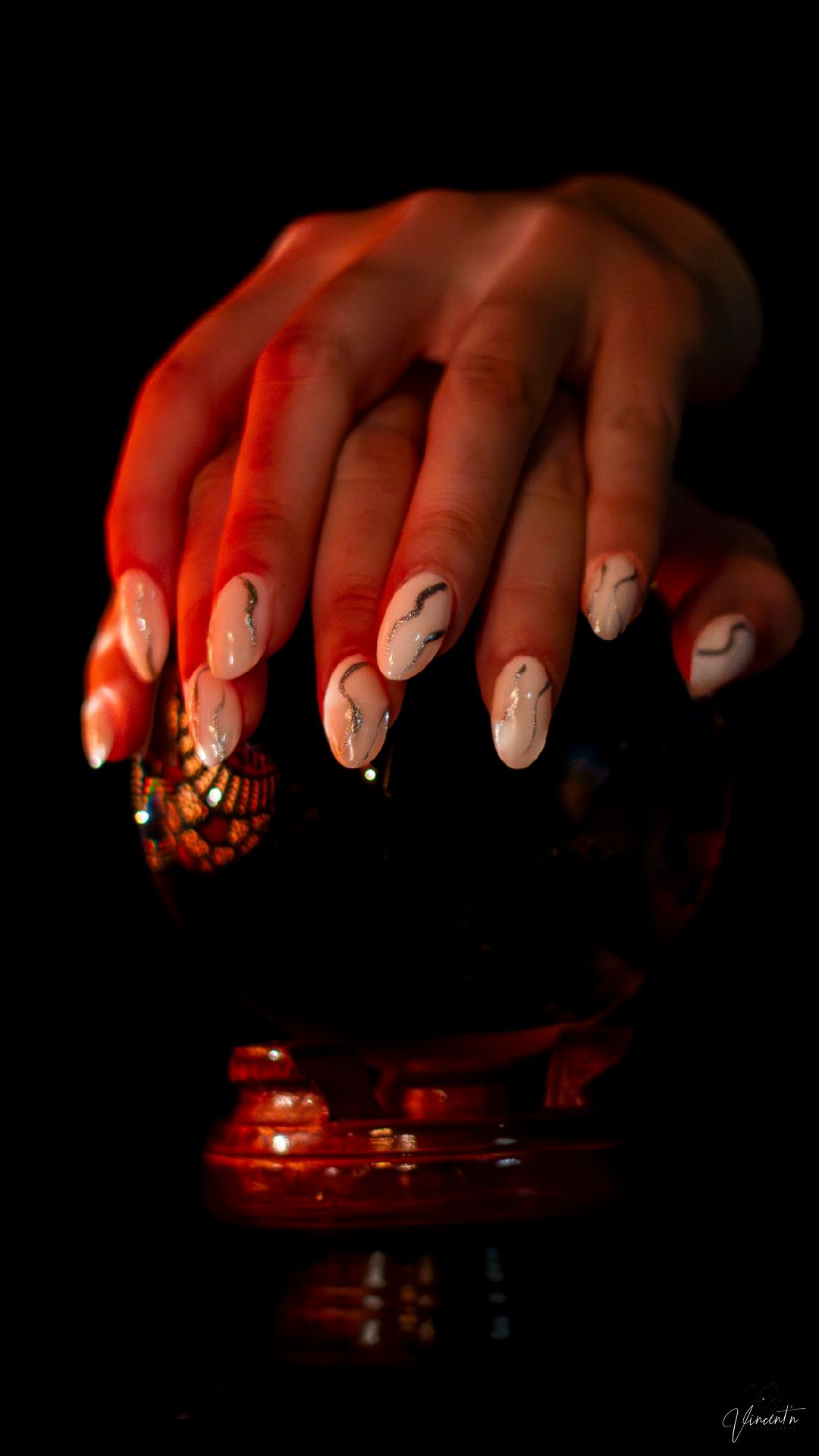 Artistic macro shots of decorated fingernails with red lighting on dark background.