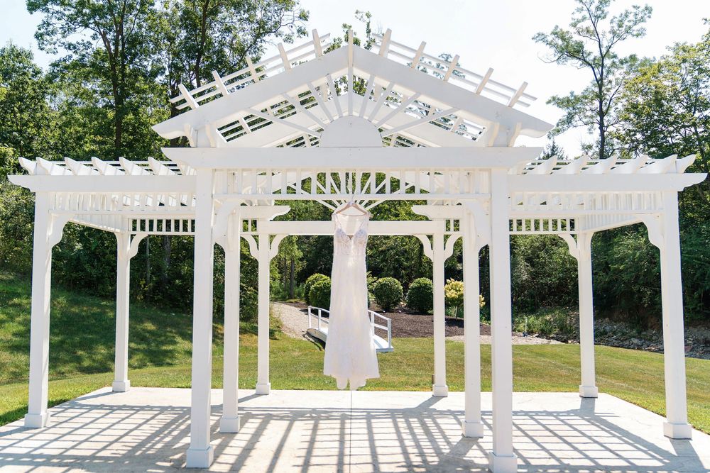 Detail shot of bride's wedding dress hanging at the ceremony's arch at The Magnolia Estate Rosewood Manor: Cincinnati wedding photographer