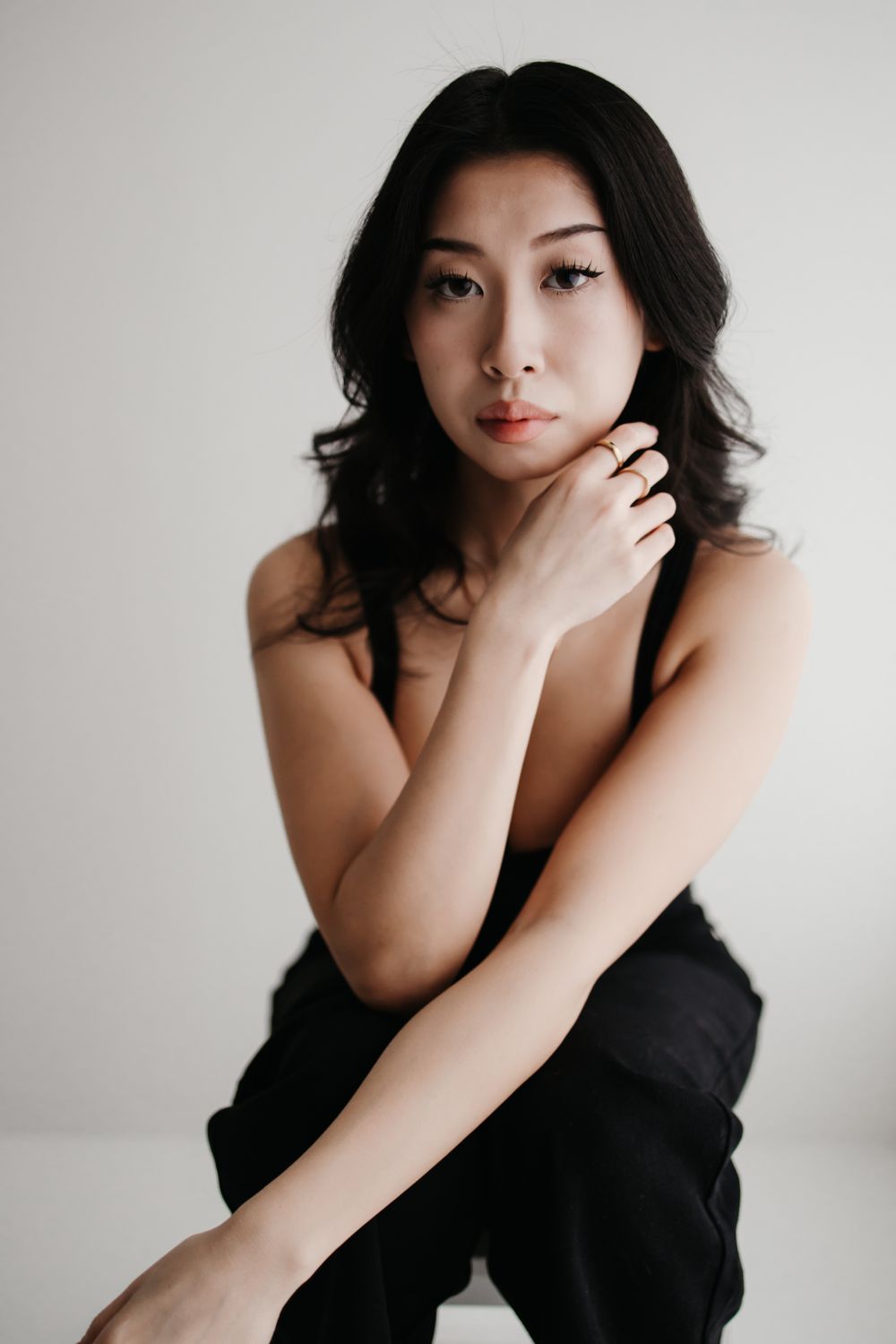 A series of artistic portrait photographs showing a person in black clothing against a white background.