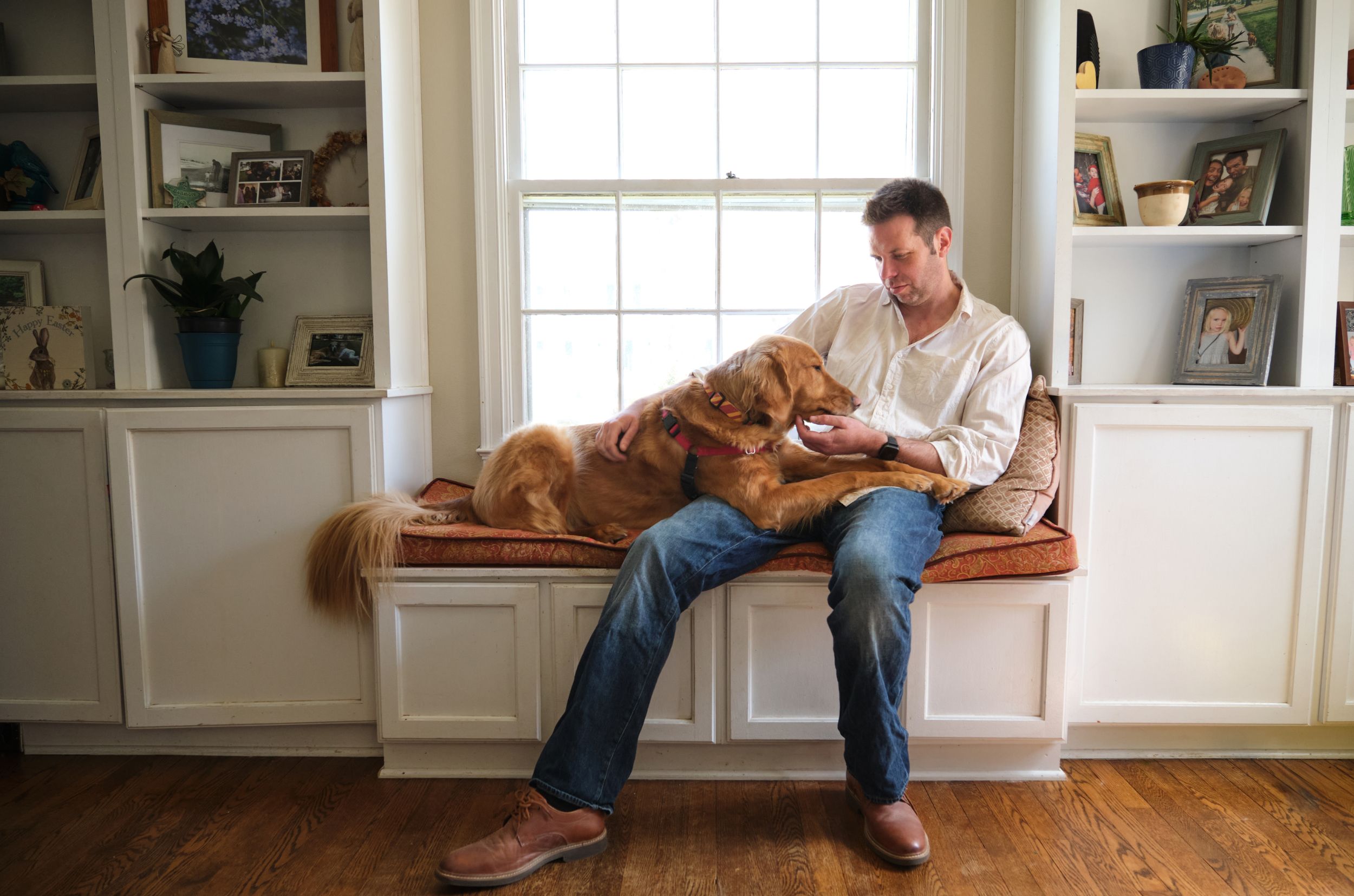 A man sits with his dog, a golden retriever, for a series of portraits