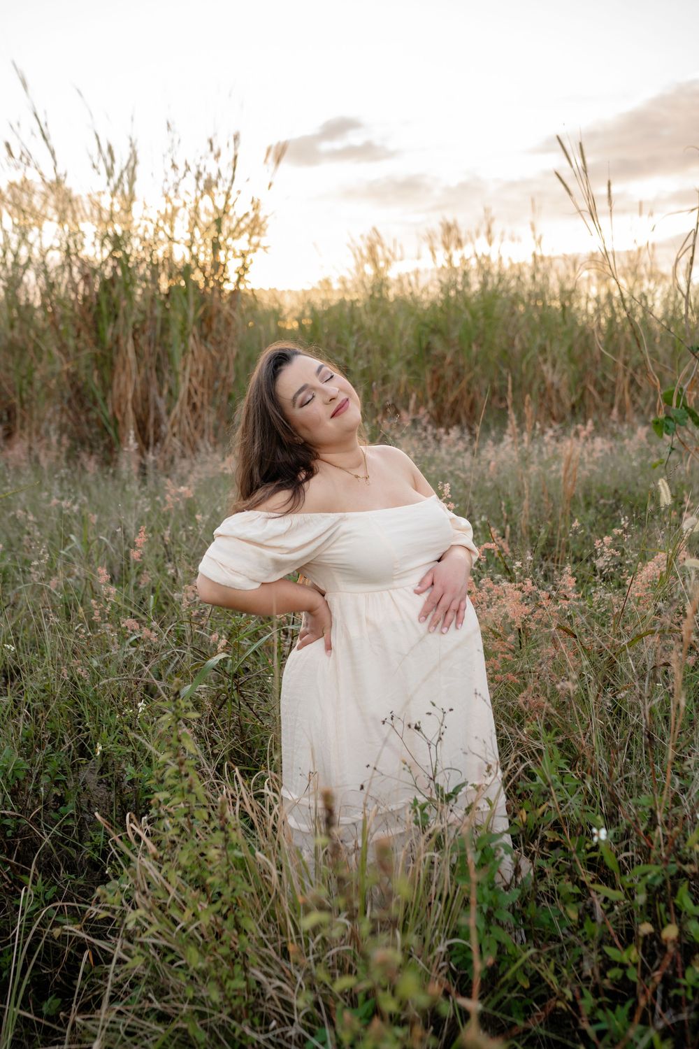 Woman in cream dress twirling joyfully in a wildflower field at sunset.