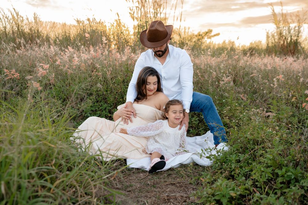 Tender family moment captured in a golden field at sunset with soft natural lighting.