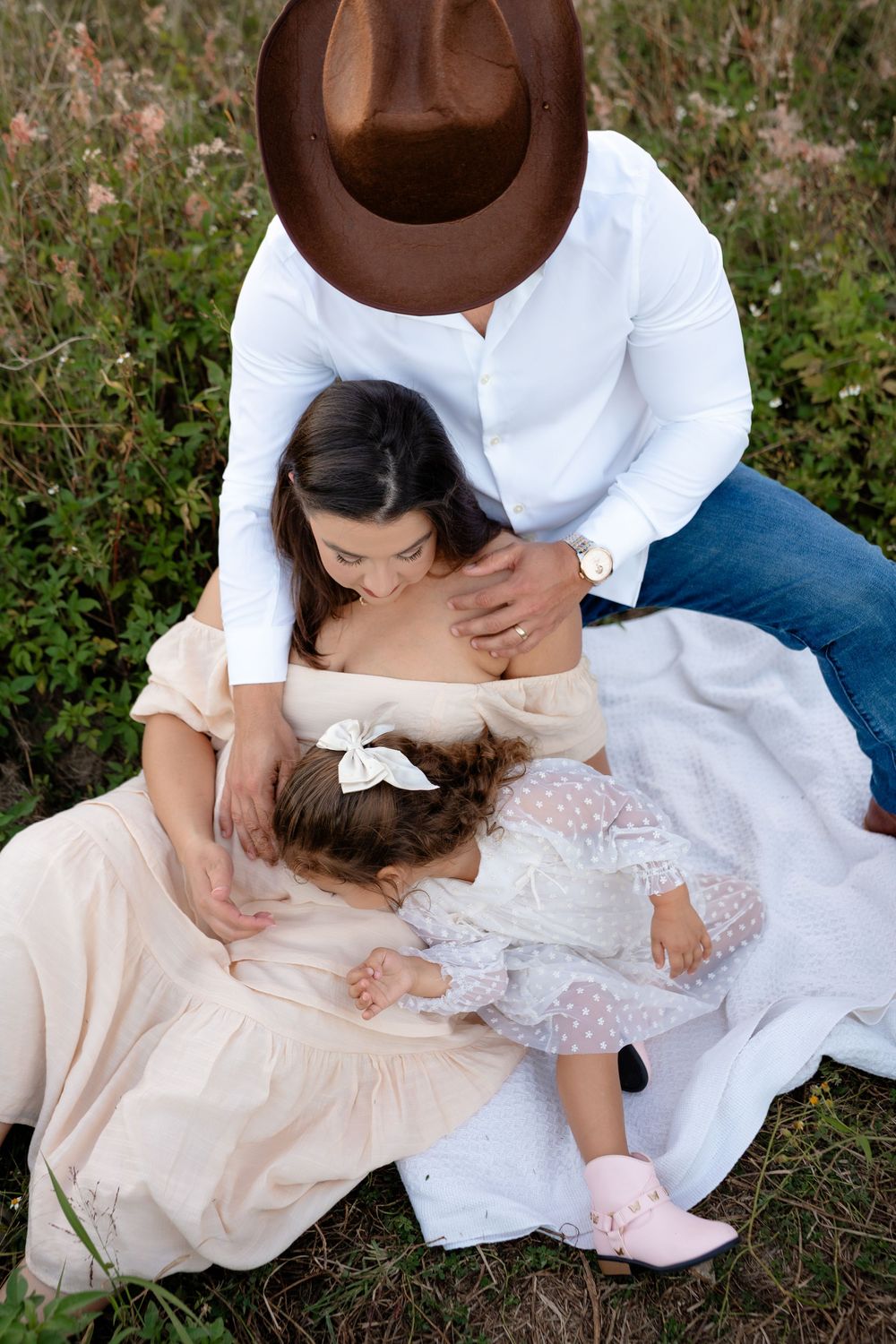 Intimate family moment captured in a wildflower meadow at sunset.