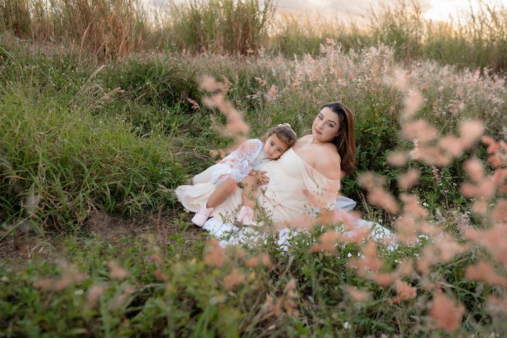 Woman in cream dress laying in field of wildflowers during sunset.