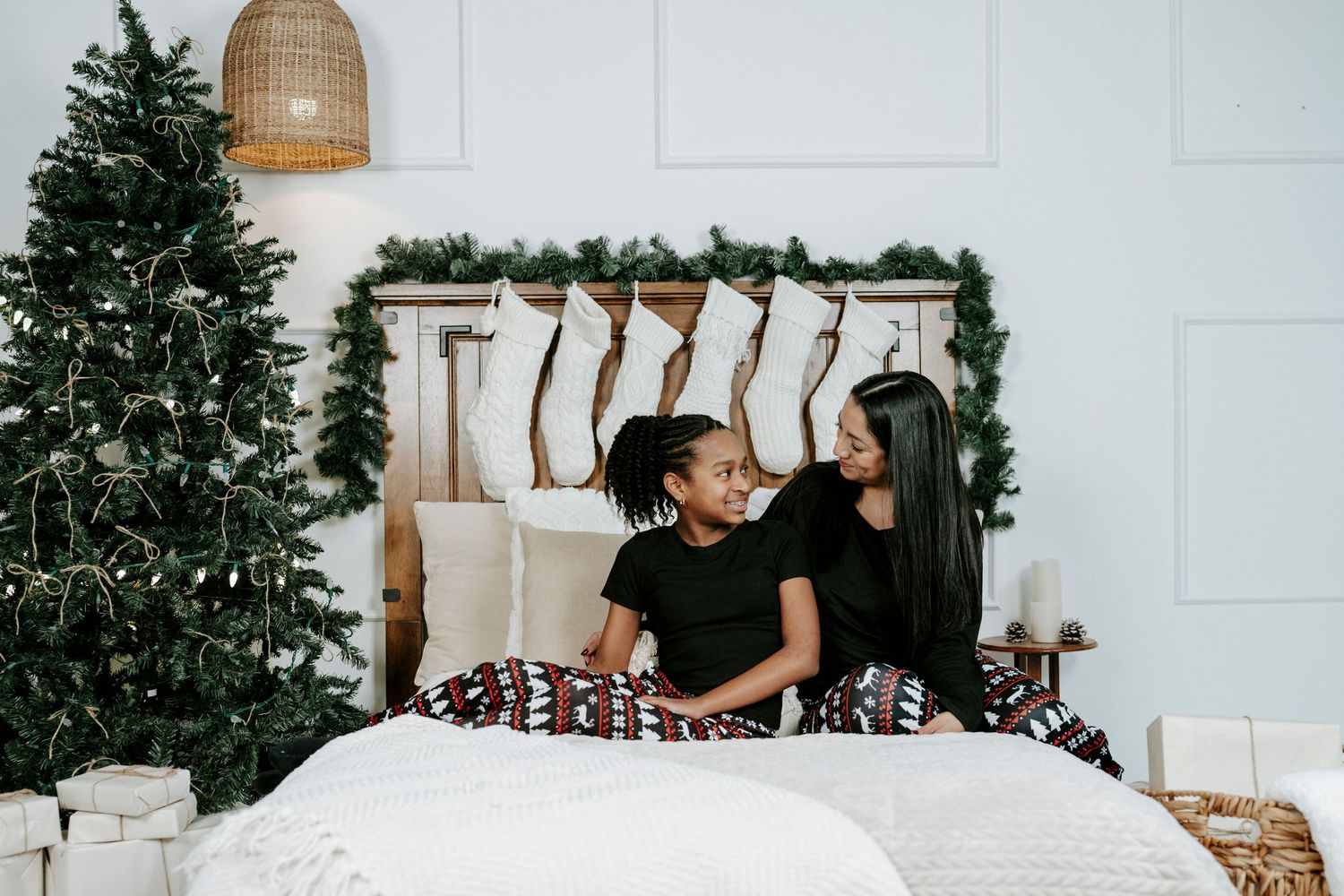 People sit together on a white couch near a decorated Christmas tree in a bright modern living room.