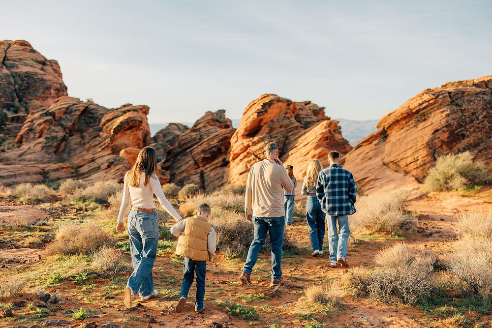 Family walking together through scenic red rock formations in desert landscape during golden hour.