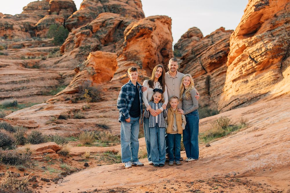 A group stands together on red rock formations in a desert landscape during golden hour lighting.
