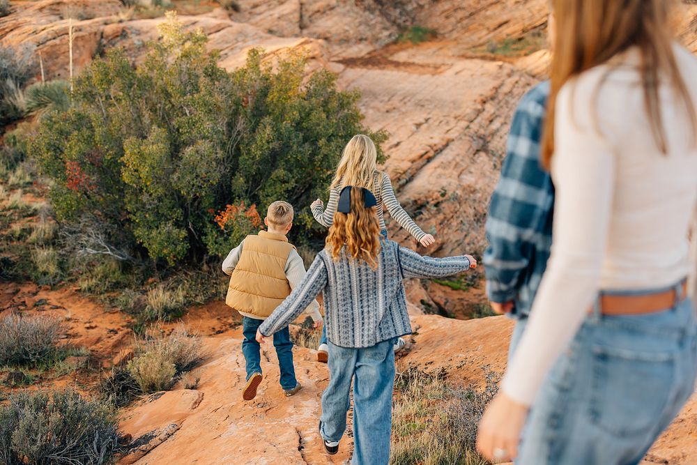 A couple walks hand in hand along a scenic desert trail during golden hour at sunset.