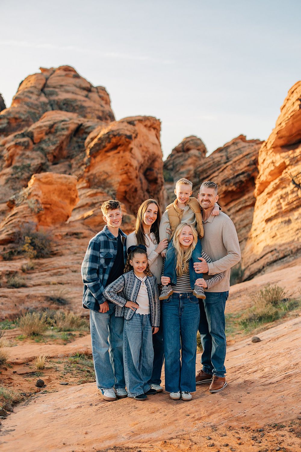 A group sits together on red rock formations at sunset in a desert landscape.