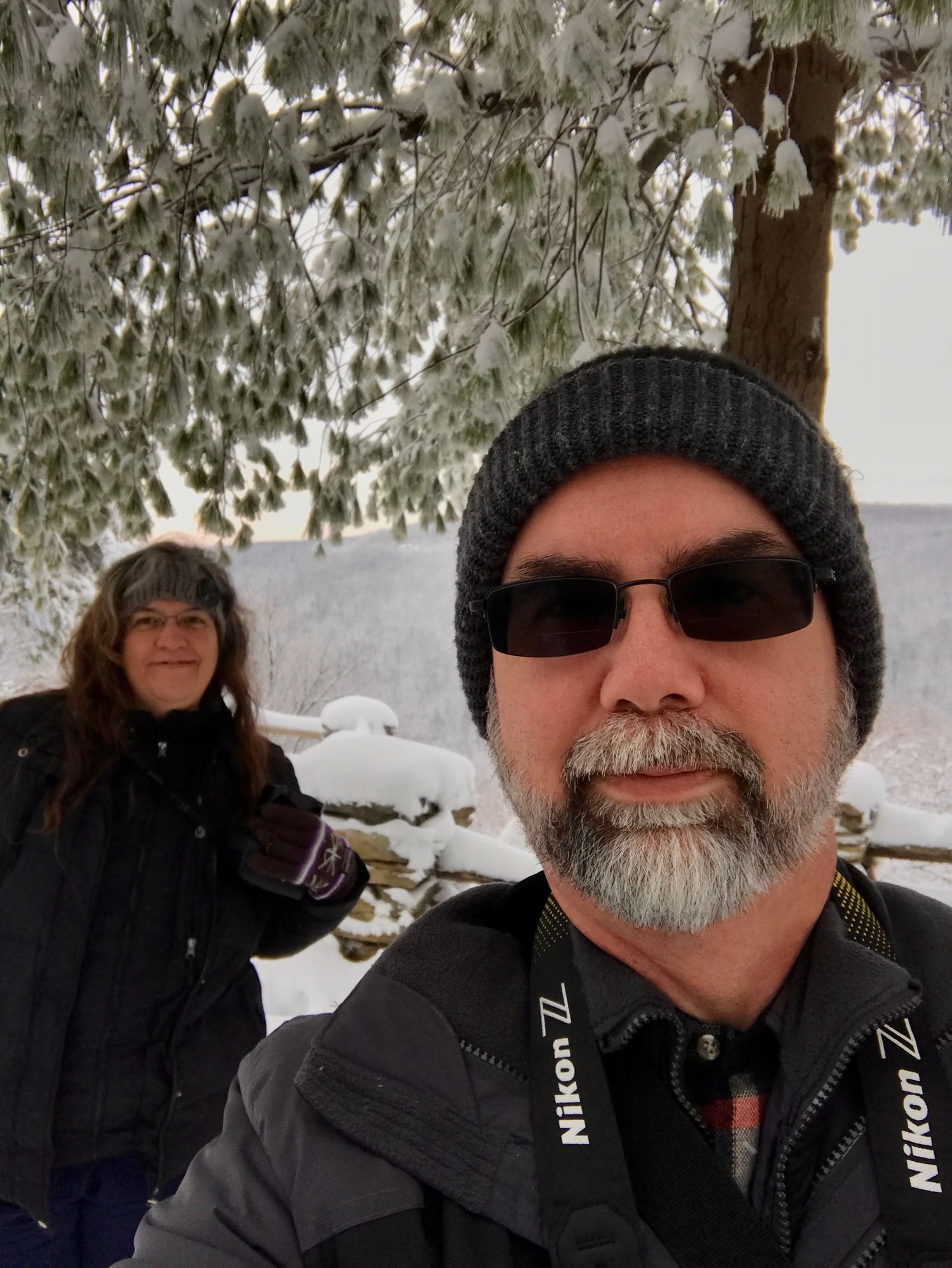 Winter scene with snow covered trees and people wearing warm winter clothing and hats.