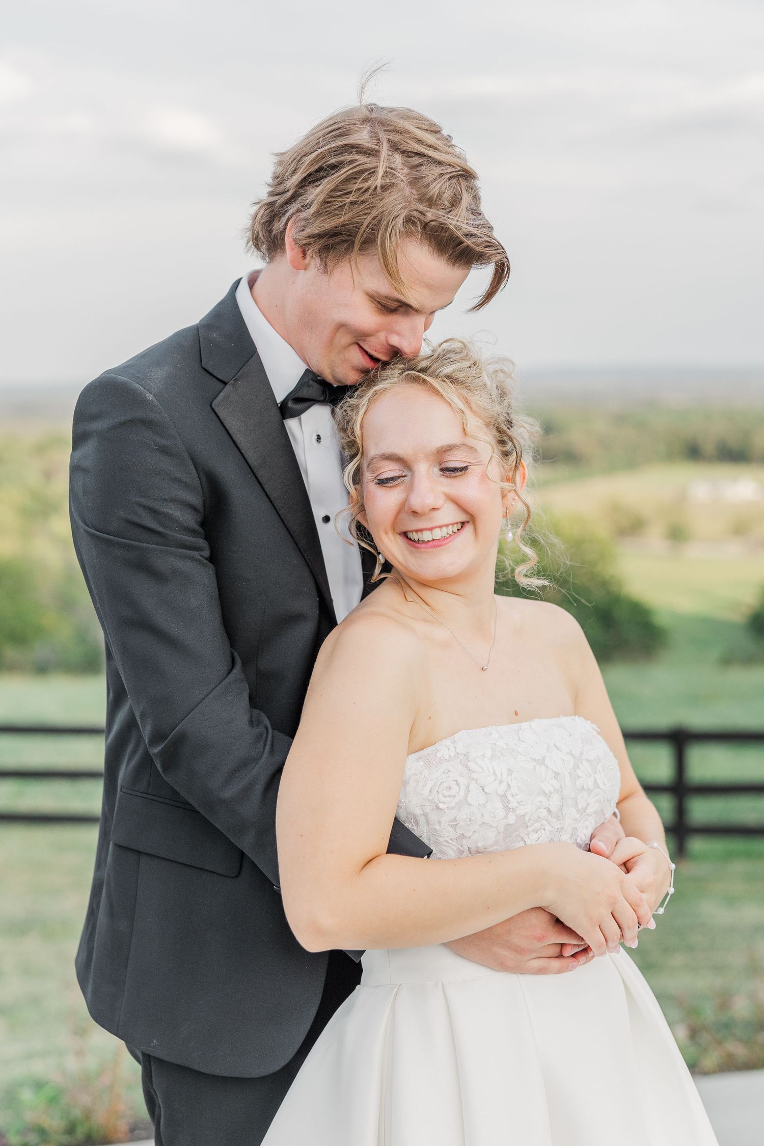 A tender embrace captured against a scenic countryside backdrop.