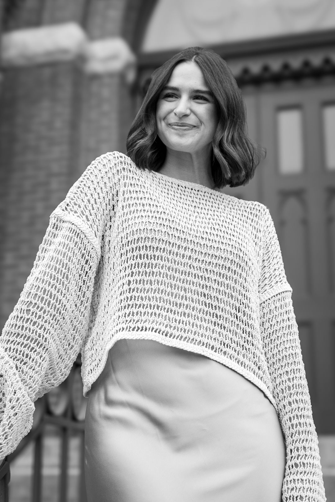 Black and white portrait showcasing a knit sweater against architectural backdrop.