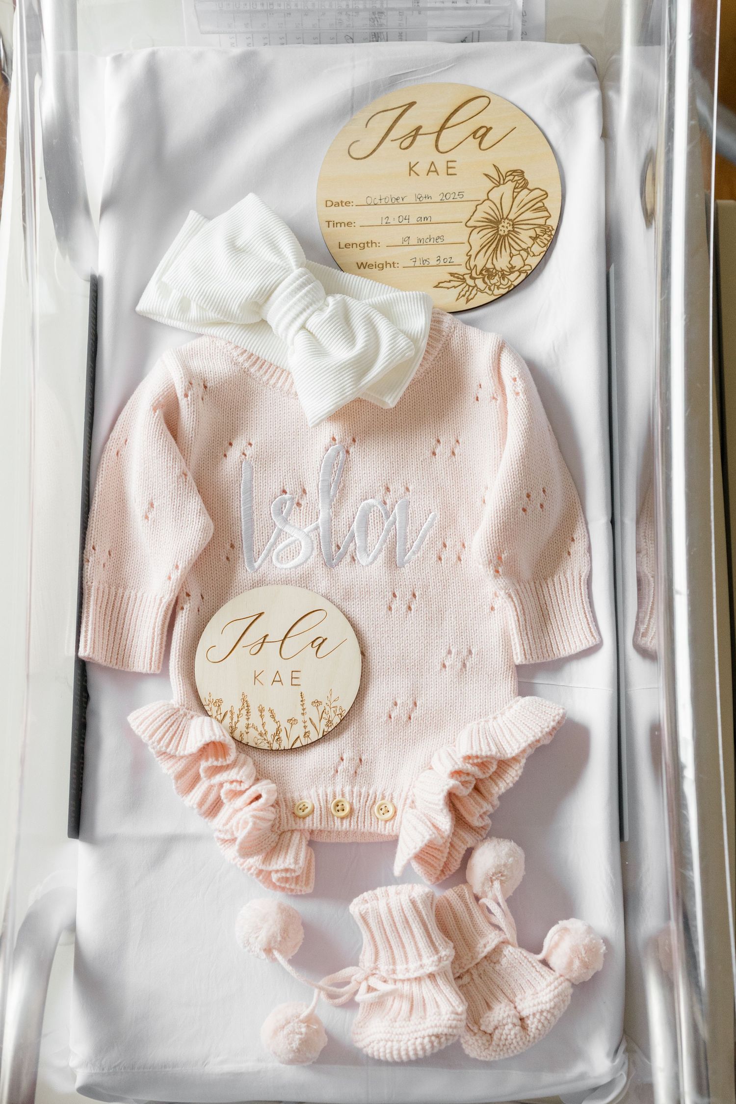 Delicate pink baby clothing sets with matching knit accessories displayed in transparent packaging with decorative tags.