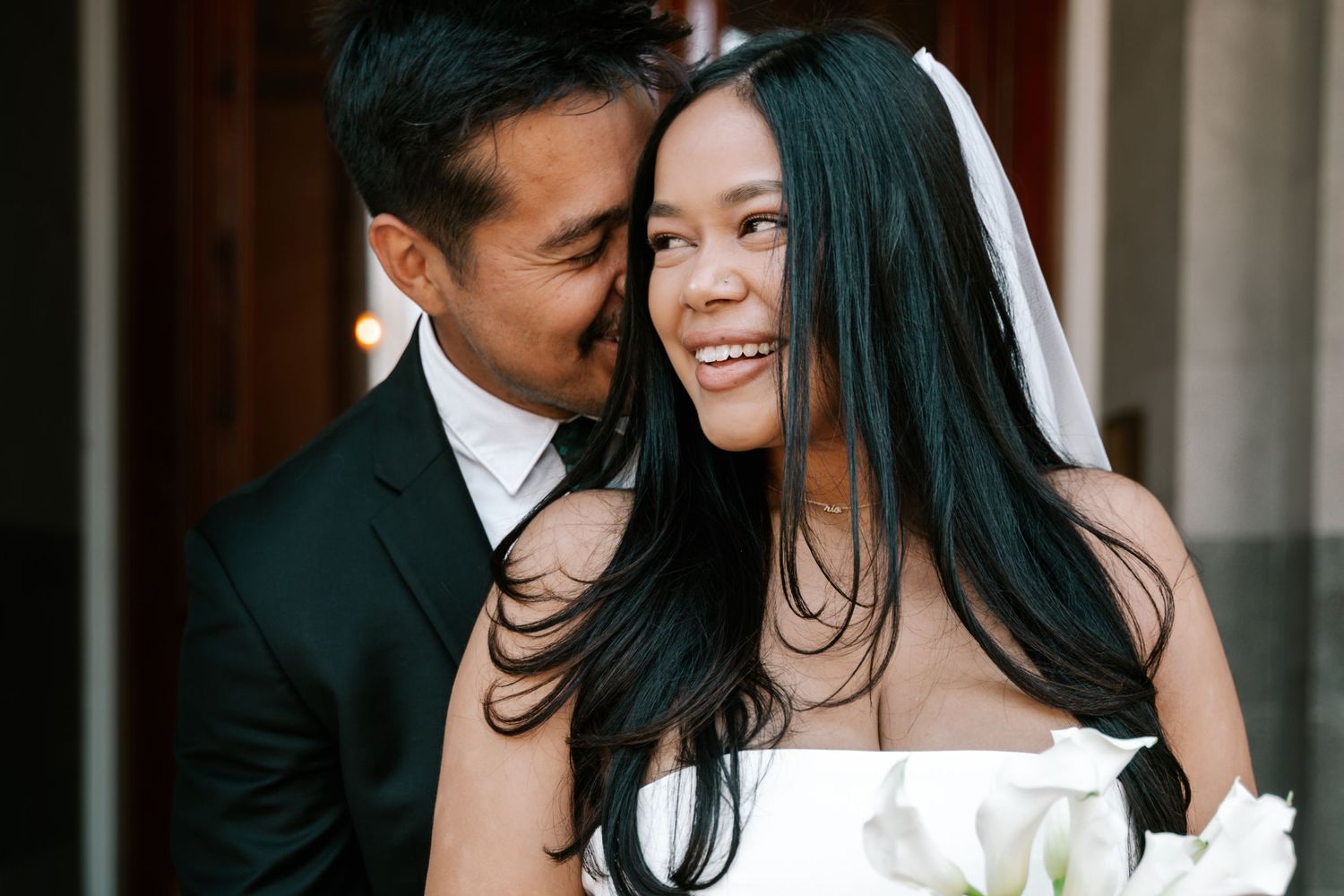 Couple in formal wedding attire sharing an intimate moment together in an elegant indoor setting.