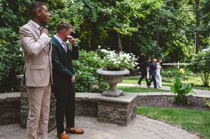 Wedding guests and party members gather for photos in a scenic garden setting.
