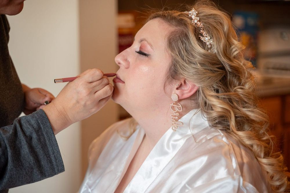Close-up of someone applying makeup with professional brushes during wedding preparation.