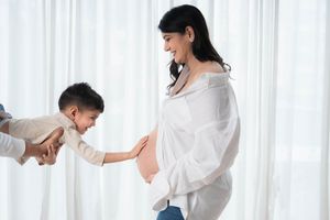 Family maternity photoshoot in Hyderabad with elder sibling gently touching the baby bump, capturing pregnancy bonding and motherhood.