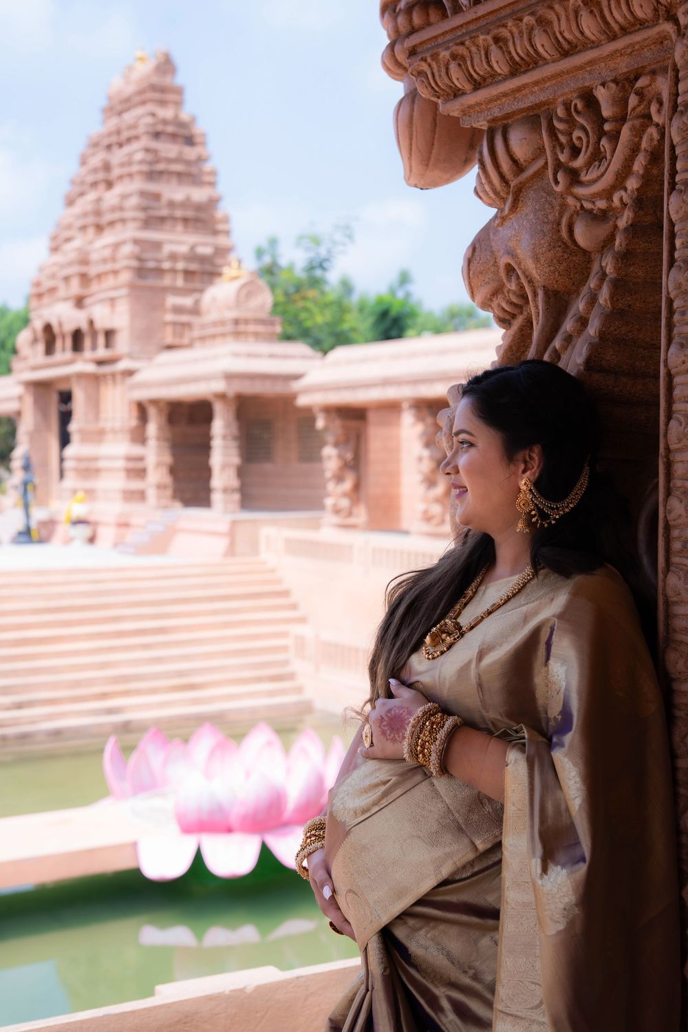 Pregnant woman in saree posing near temple architecture during traditional maternity photoshoot in Hyderabad