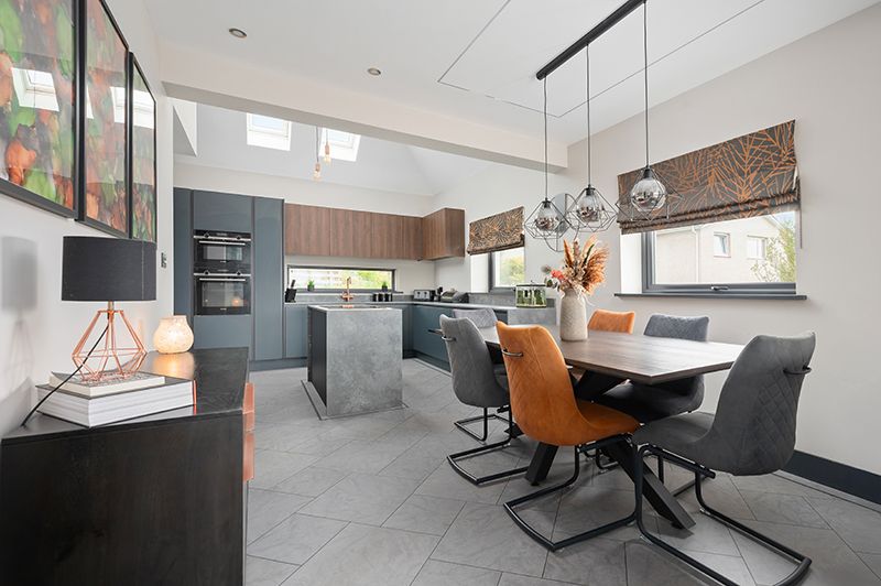 Modern open concept kitchen and dining area with gray tile floors, pendant lighting, and cognac leather dining chairs.