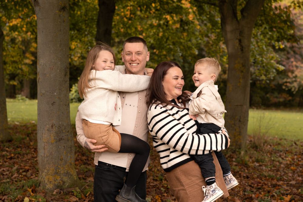 A group enjoys a warm autumn day together outdoors among fallen leaves and trees in a park setting.